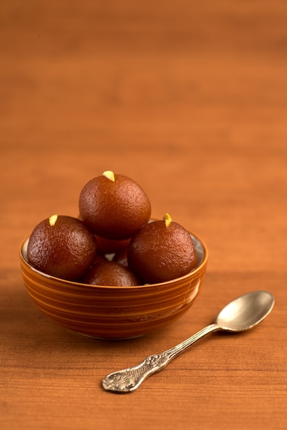 Gulab Jamun in bowl on wooden table. Indian Dessert or Sweet Dish.