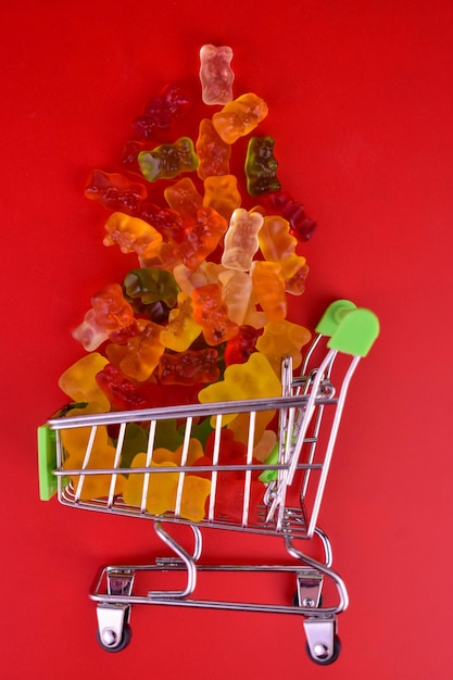 Gummy bears in a small supermarket basket on a red background.