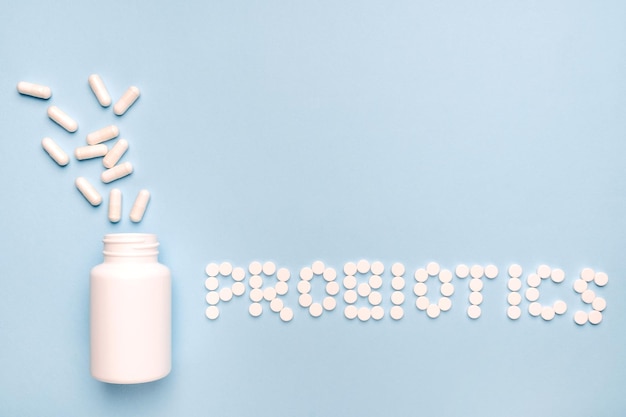 Guts protection Probiotics word made of pills medicaments pills spilled from a white bottle On blue background