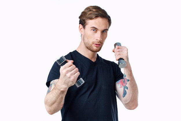 Guy athlete in a black tshirt with dumbbells in his hands on a white background