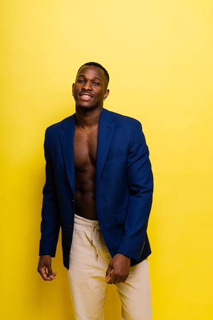 Guy in blue suit on yellow background handsome athletic man in jacket smiling