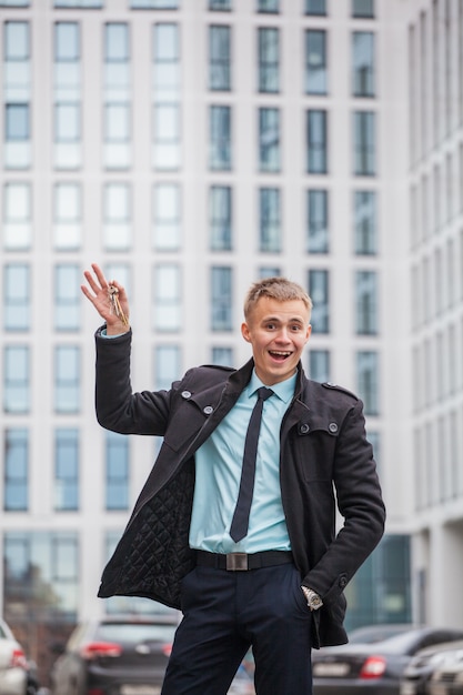 guy in business style clothes on the background of a tall building with keys to new housing