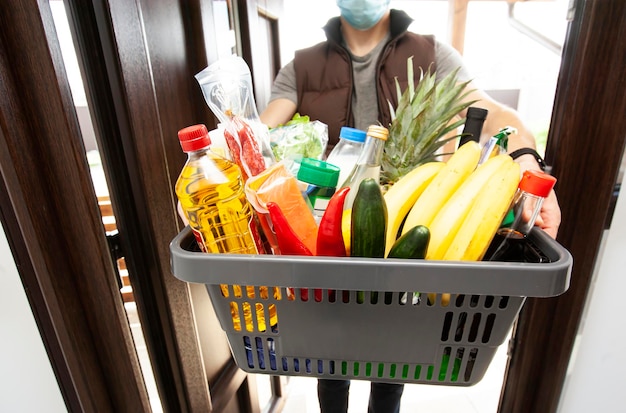 The guy delivers the basket full of groceries to the door of the house Online shopping