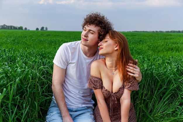 A guy and a girl are hugging on a green field