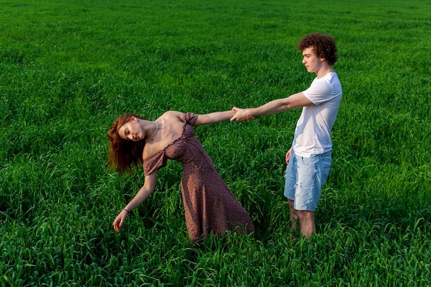 A guy and a girl are hugging on a green field