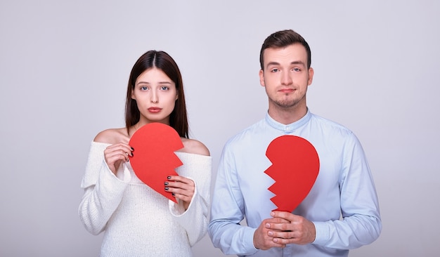 Guy and girl holding two pieces of broken heart on white background