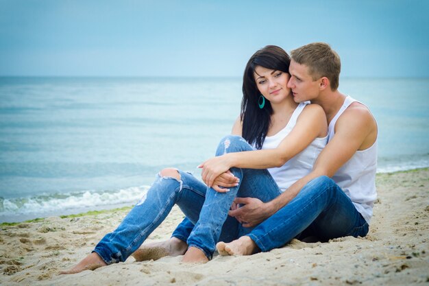 Guy and a girl in jeans and white t-shirts on the seashore