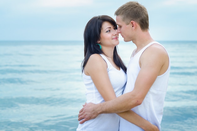 Guy and a girl in jeans and white t-shirts on the seashore