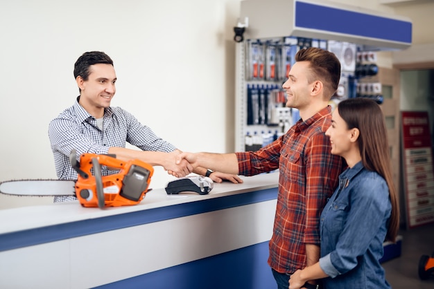 Guy and girl pay for the purchase of a chainsaw.