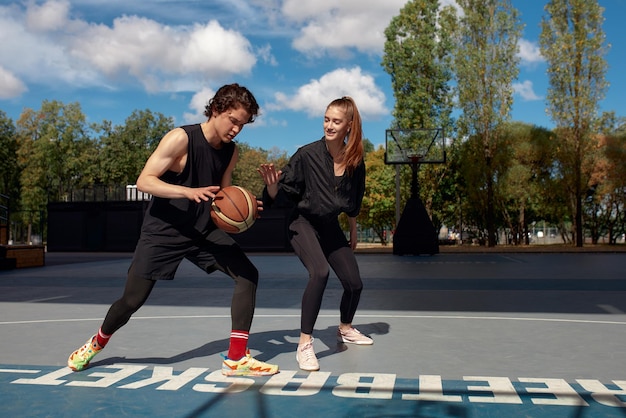 Guy and girl playing basketball on the city playground