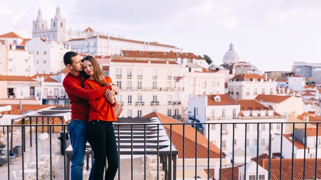 Guy and girl in red sweaters in each other's arms. city panorama.