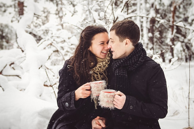 A guy and a girl in warm clothes and scarves on a walk in the snowy forest and in the field