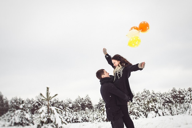 A guy and a girl in warm clothes and scarves on a walk in the snowy forest and in the field