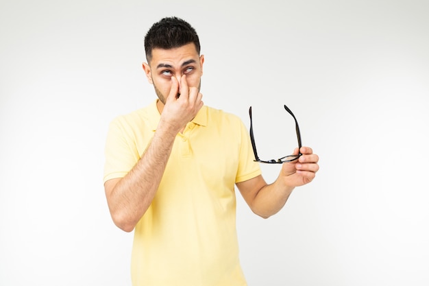 Guy has dry eyes taking off glasses on a white background