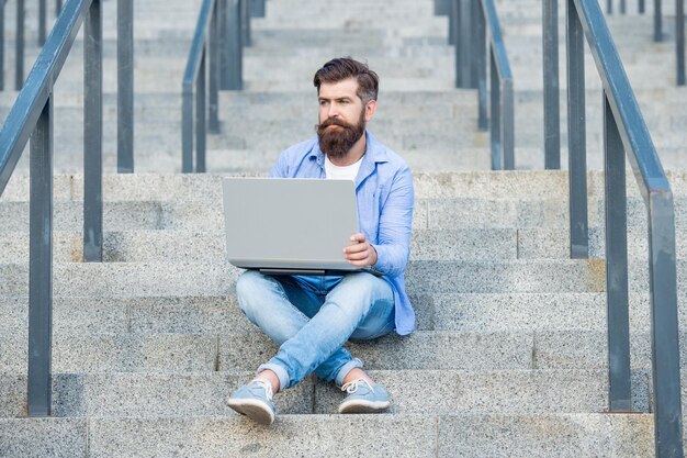 Guy has online video laptop communication outside guy has online video communication