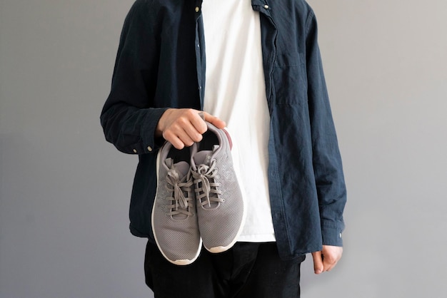 A guy holding a pair of classic sneakers simple trendy casual style