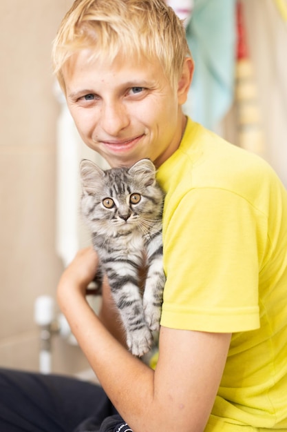 The guy holds a fluffy kitten in his arms