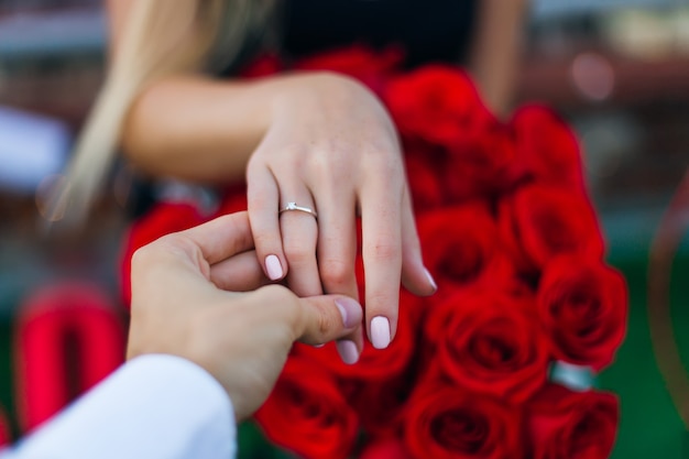 The guy holds the girl's hand and shows the golden ring on on the ring finger