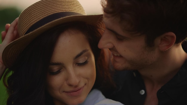 Guy hugging girl behind in park Smiling couple expressing tenderness outdoors