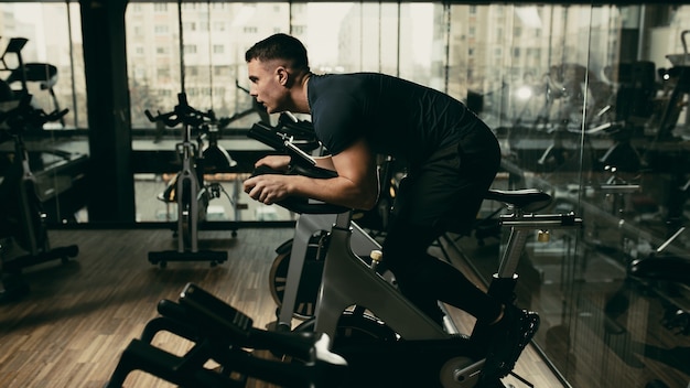 The guy is engaged in a bicycle simulator in the gym.