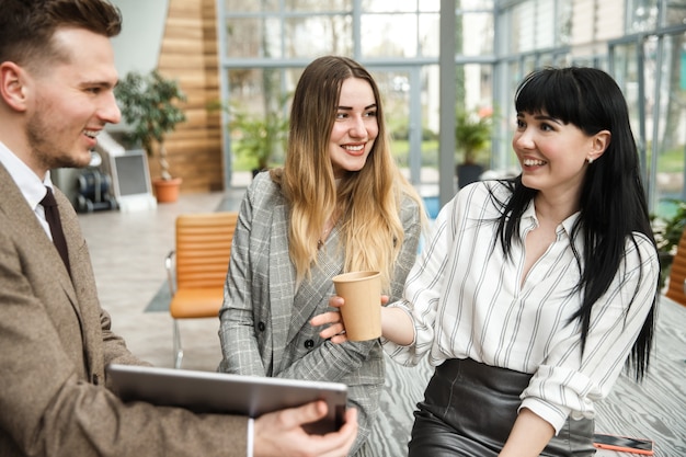 A guy is showing something on his tablet to a two girls