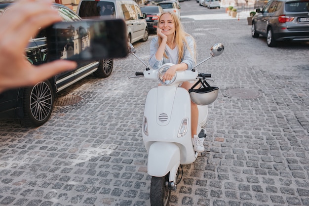 Guy is taking picture of woman in helmet sitting on motorcycle