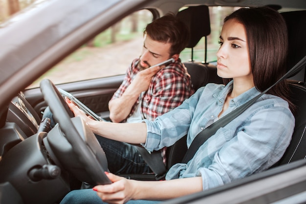 Guy is talking on the phone while girl is driving