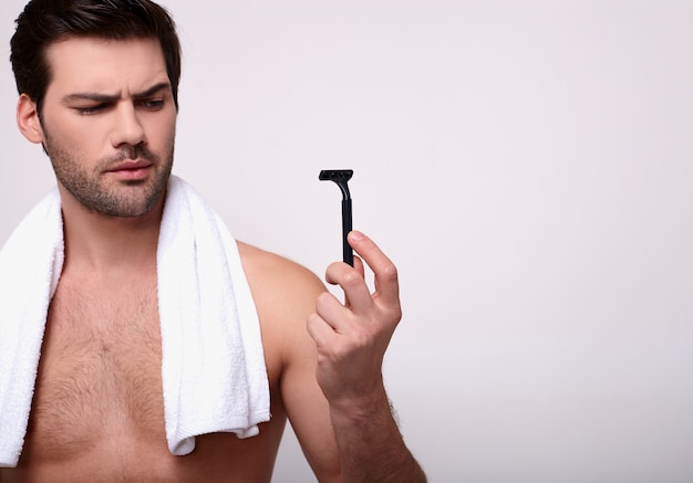 The guy looks at the razor and thinks whether to shave