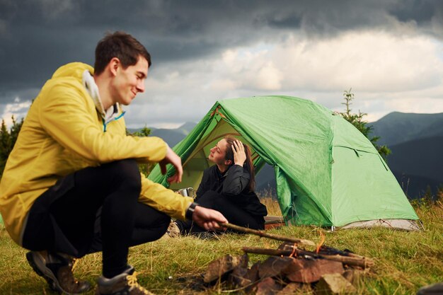 Guy making campfire Girlfriend just woke up Majestic Carpathian Mountains Beautiful landscape of untouched nature