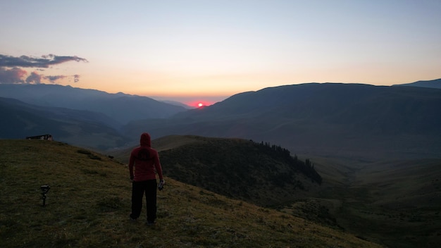 A guy in the mountains is watching the sunset