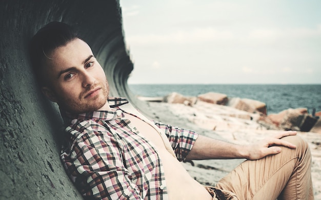 Guy in a plaid shirt posing against the background of the sea, you can see part of the face close-up