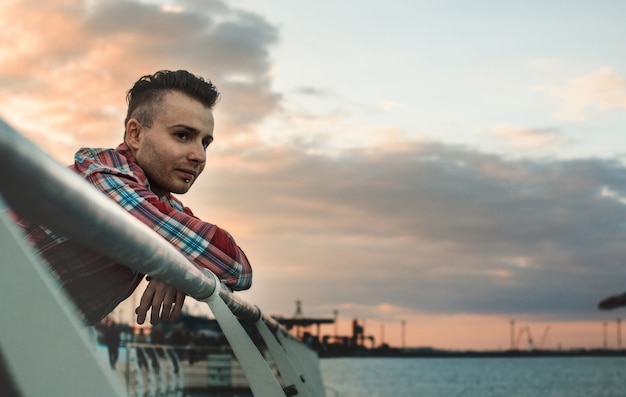 Guy in a plaid shirt posing against the background of the sea, you can see part of the face close-up