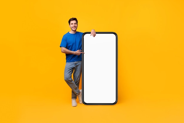 Guy pointing and leaning on big white empty smartphone screen