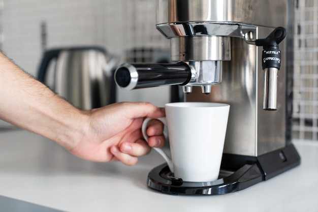 Guy prepare delicious aromatic coffee in a coffee machine. A simple way to make coffee