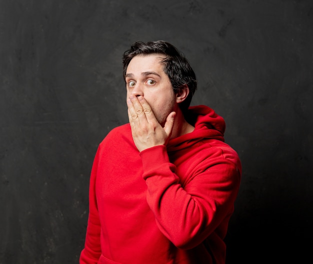 Guy in red sweatshirt show quiet gesture on dark wall