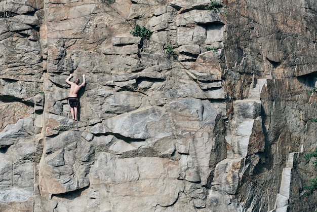 Guy's climbing rocks and looks in top, extreme. Crested surface, in cracks. Rock. Stone walls. fearless person.