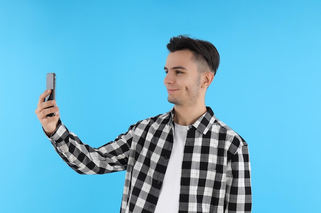 Guy in shirt with phone on blue background