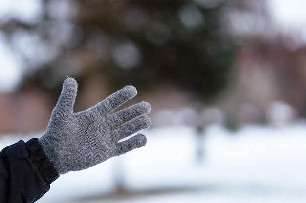 The guy shows the class in gloves Hands in gray winter gloves Palm with a glove in the snow The guy threw snow