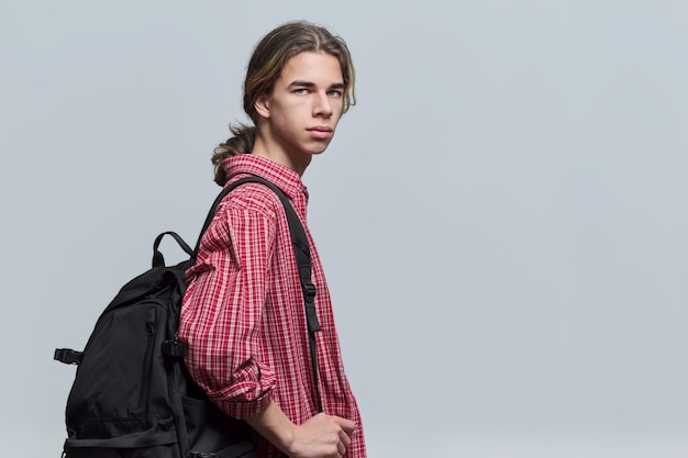 Guy student teenager with backpack looking at camera on light background