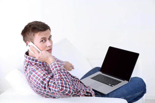 Guy talking on phone on sofa on white background