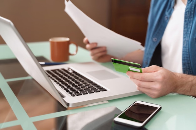 Guy using computer and credit card to pay domestic bills online