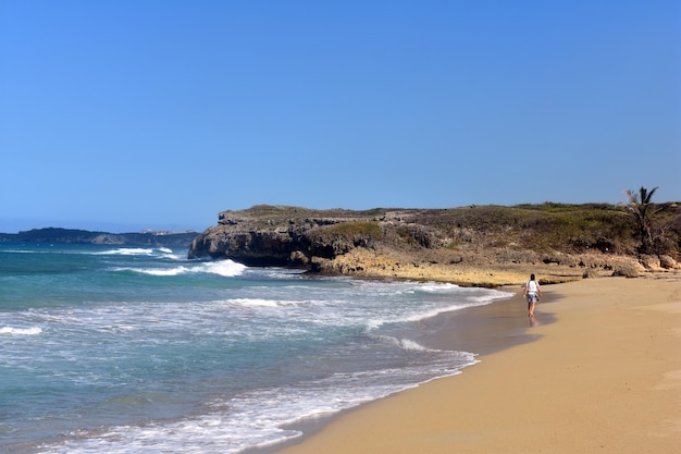 Guy walks on a sandy ocean beach