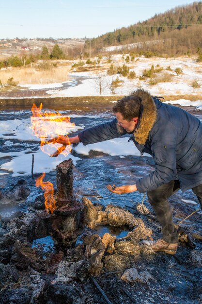 The guy warms his hands in the fire mud volcano Starunya Geological monument of nature In the foothills of the winter Ukrainian Carpathians