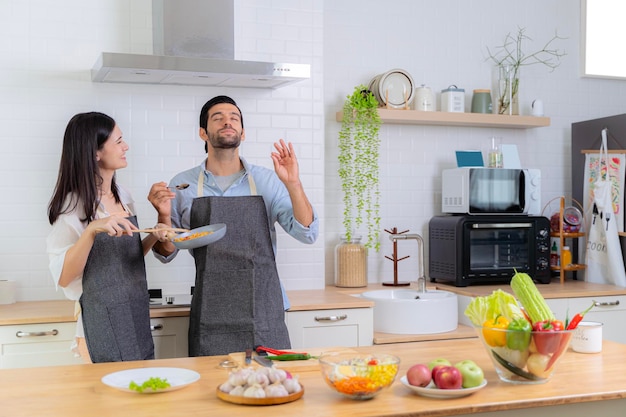 The guy was very happy tasting his girlfriend's cooking skills A young couple in love having fun while preparing a breakfast together on a beautiful morning