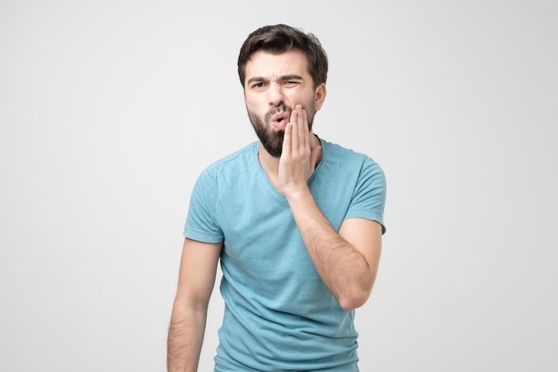 Guy wearing blue shirt with tooth ache isolated on white background