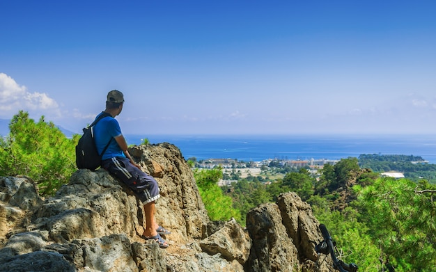 A guy with a backpack on top of the mountain Olympos looks at the city of Kemer in Turkey.