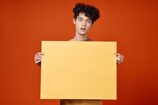 Guy with curly hair island in hands advertising red background