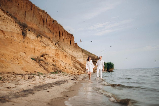 A guy with a girl in white clothes on the seashore