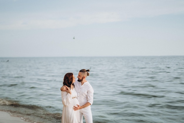 A guy with a girl in white clothes on the seashore