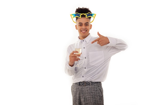 Guy with huge star goggles and a glass of champagne pointing his finger at it and wearing a shirt